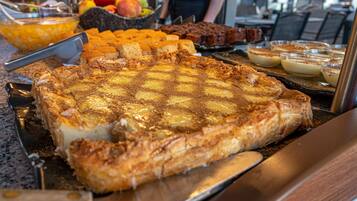 A buffet with various desserts including a large pie, fruit, and other baked goods.