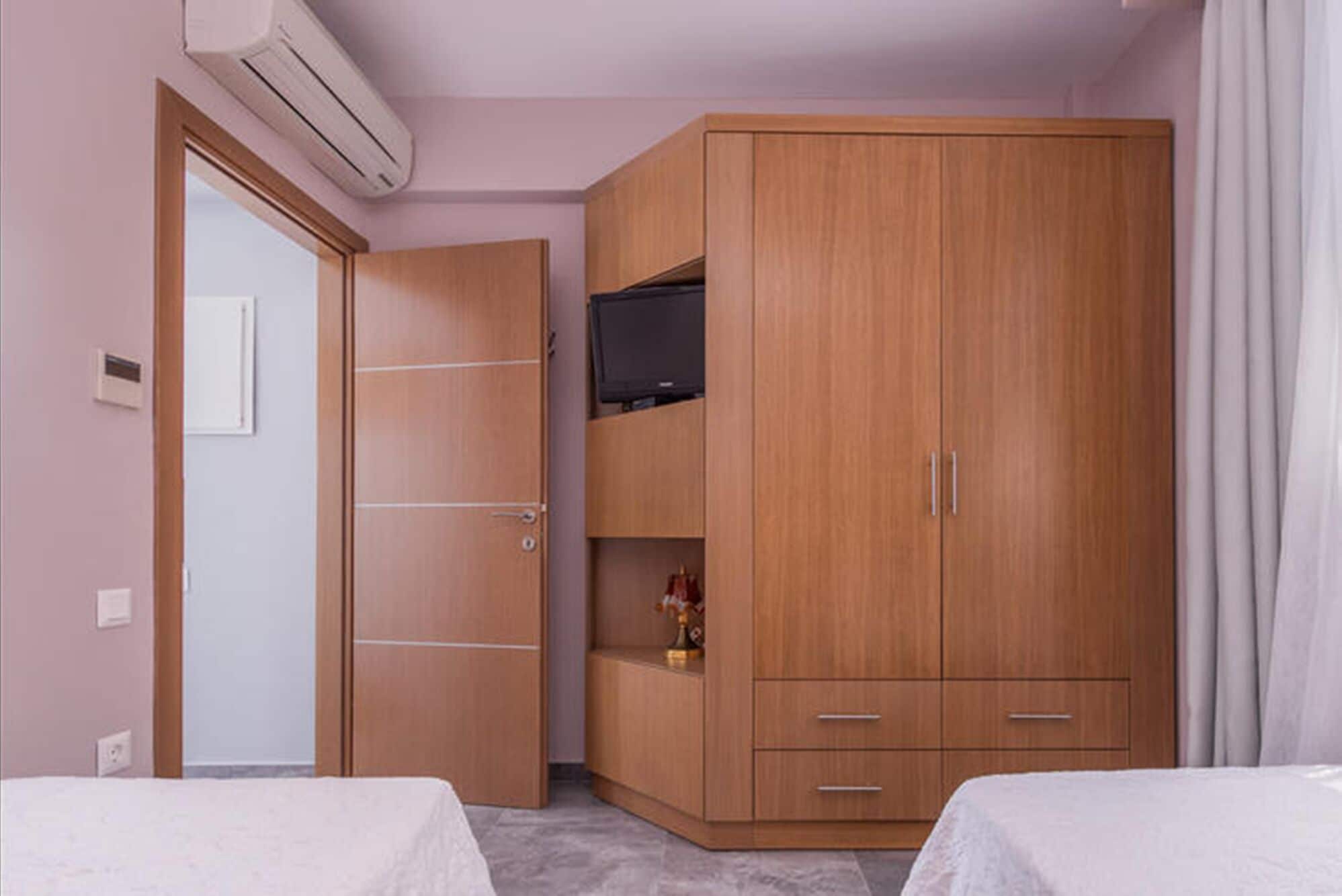 Ein Zimmer mit Kleiderschrank, Bett und Fernseher.
