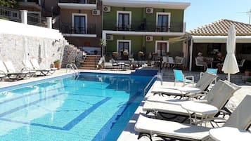 Una piscina al aire libre, sombrillas, sillones reclinables de piscina