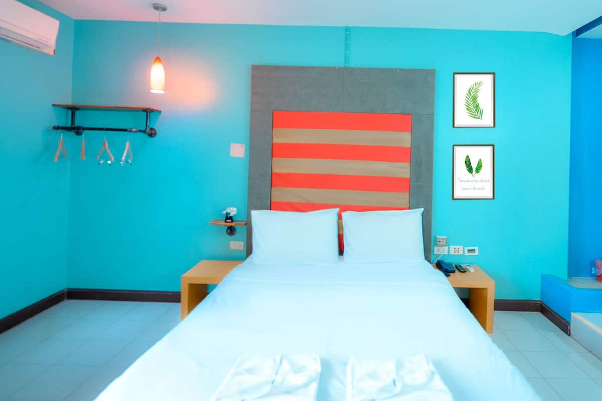 Een moderne hotelkamer met een groot bed, een hoofdbord met horizontale strepen, een nachtkastje met een lamp en een raam met uitzicht.