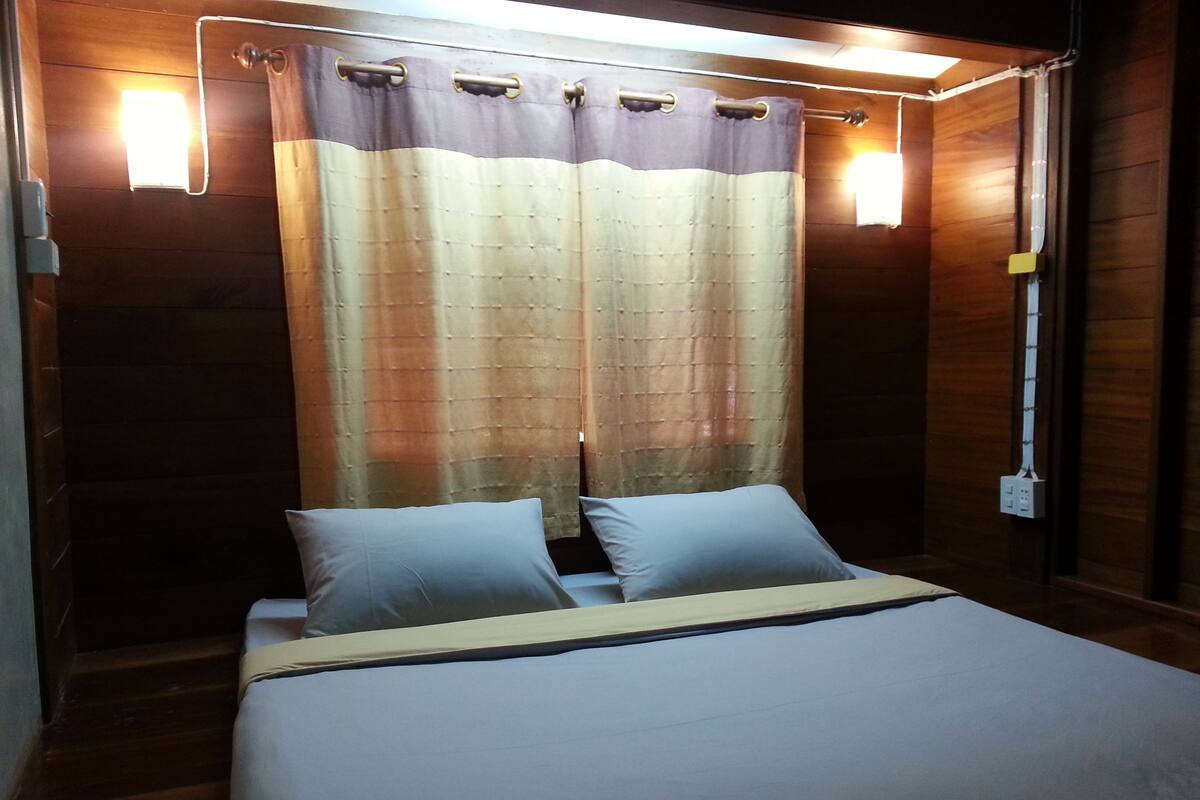 Quarto de hotel com cama, cortinas e luminárias fixadas na parede.