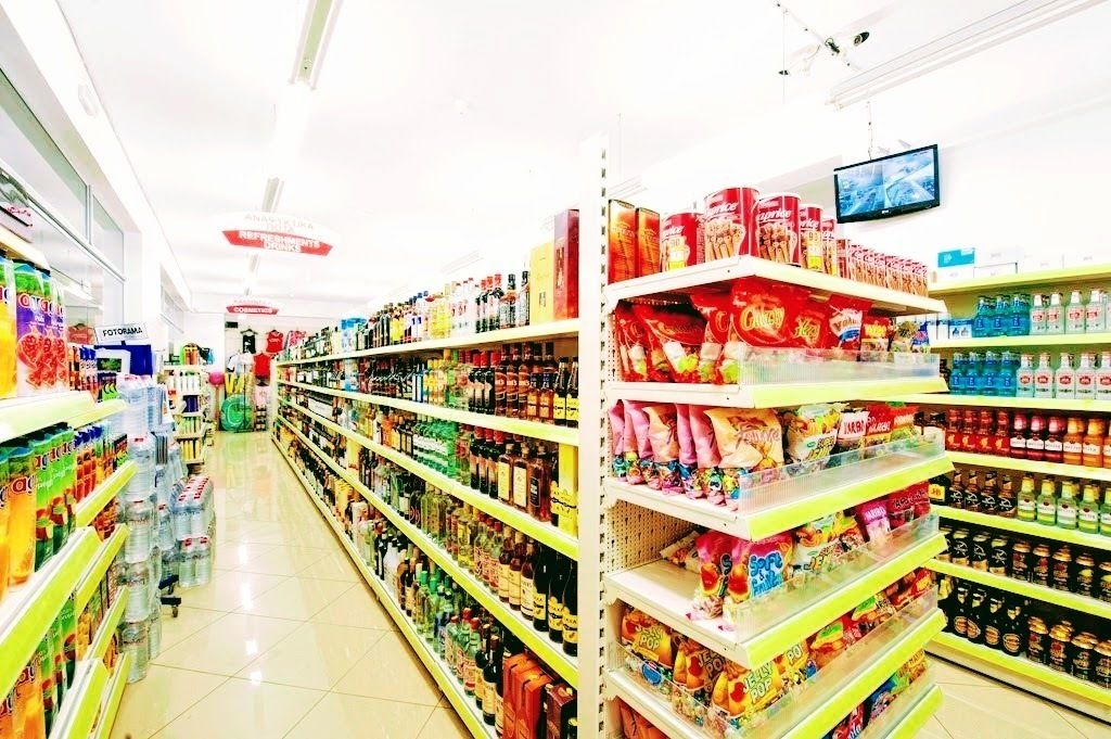 A supermarket aisle with shelves stocked with various products including beverages, snacks, and household items.