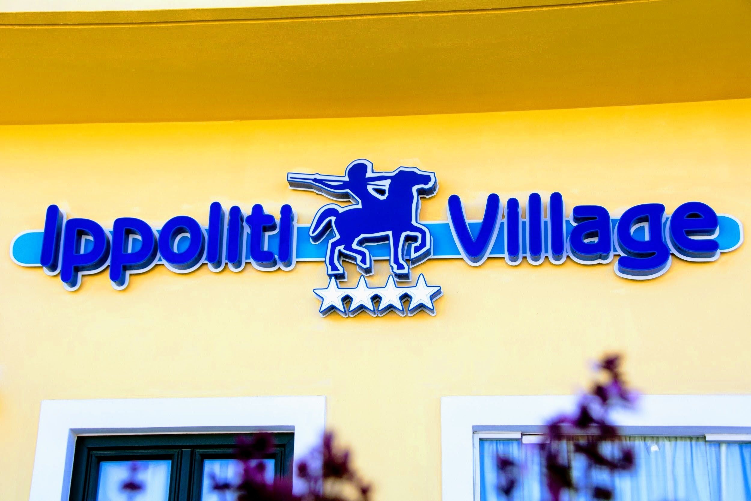 A sign with the text "Ippoliti Village" and a silhouette of a person riding a horse.