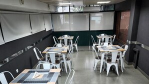 A conference room with white metal chairs and tables, a tiled floor, and a projector screen at the front. - Hotel Atlantis 2 (Maputo)