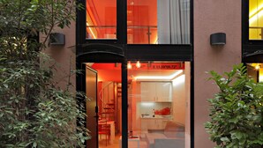 A modern building with a glass entrance, a staircase leading to an upper level, and a visible kitchen area with a sofa and dining table. - Residence Park (Zagreb)