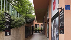 A corridor with signs for a dental studio and a residence park, a metal gate, and a no parking sign. - Residence Park (Zagreb)