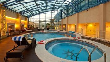 Relax by the circular pool, surrounded by lounge chairs and a table, with a clear ceiling above.