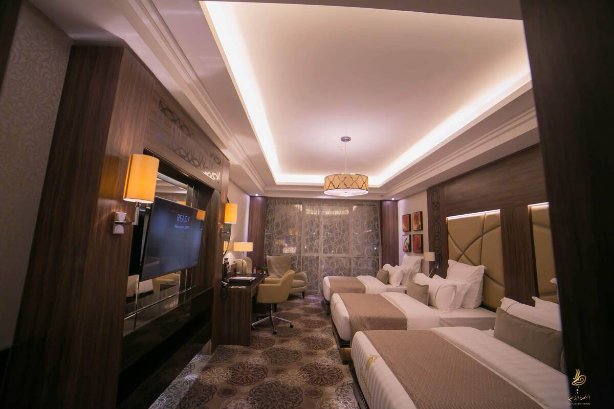 Une chambre d’hôtel équipée d’une télévision, de deux lits, d’un bureau et d’un lustre.