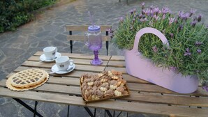 A wooden table with a pie, a basket of cookies, a potted plant, and a drink with a straw. - Residenza I Ciclamini (Rome)