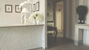A modern kitchen with a white countertop, a vase with white flowers, and framed pictures on the wall. - Residenza I Ciclamini (Rome)