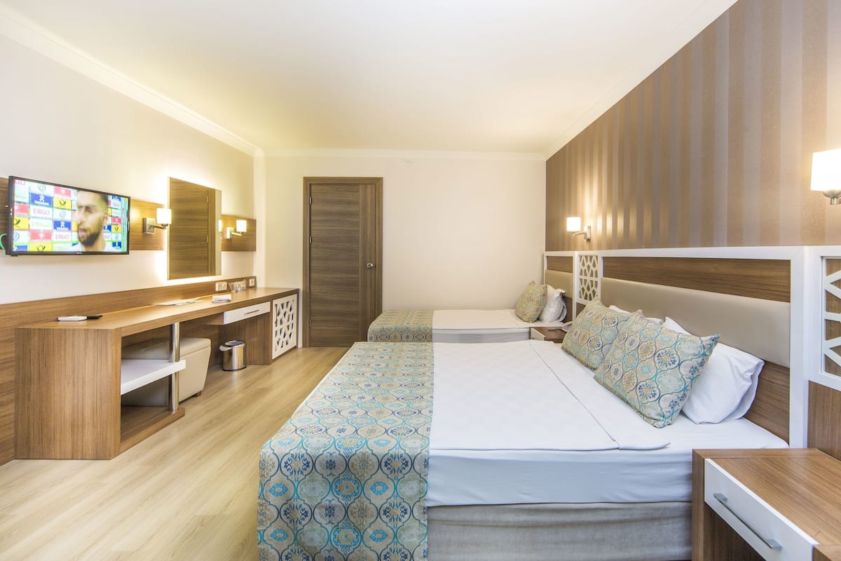 A hotel room with a bed, bedside tables, a TV, and a desk with a chair.