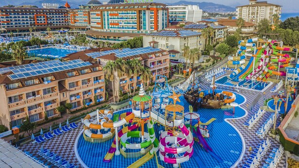 Un hotel amb diverses piscines, tobogans aquàtics i un edifici gran amb la inscripció "LONICERA" al fons.