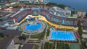 Un hotel gran amb diverses piscines, un pati central i vista al mar.