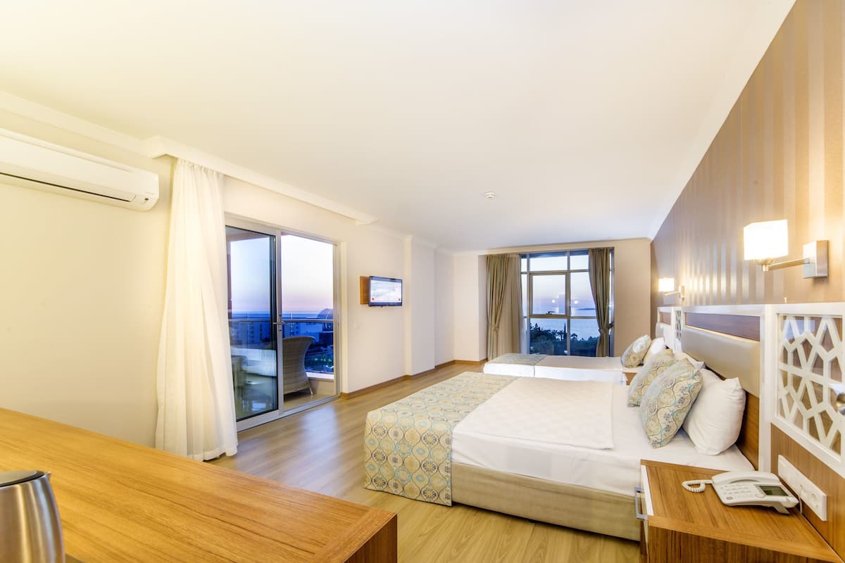 A hotel room with a bed, bedside table, and a view of the cityscape.