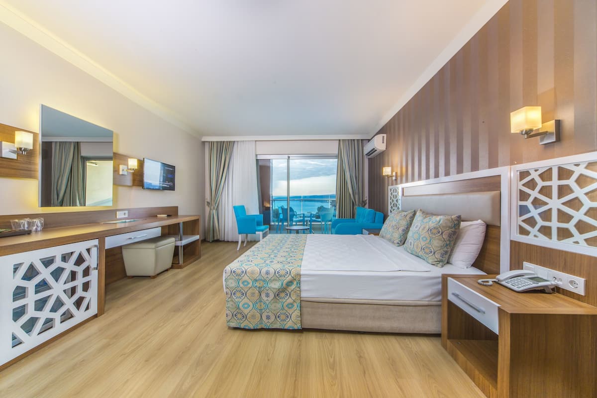 A hotel room with a large bed, a desk, a chair, and a view of the ocean.