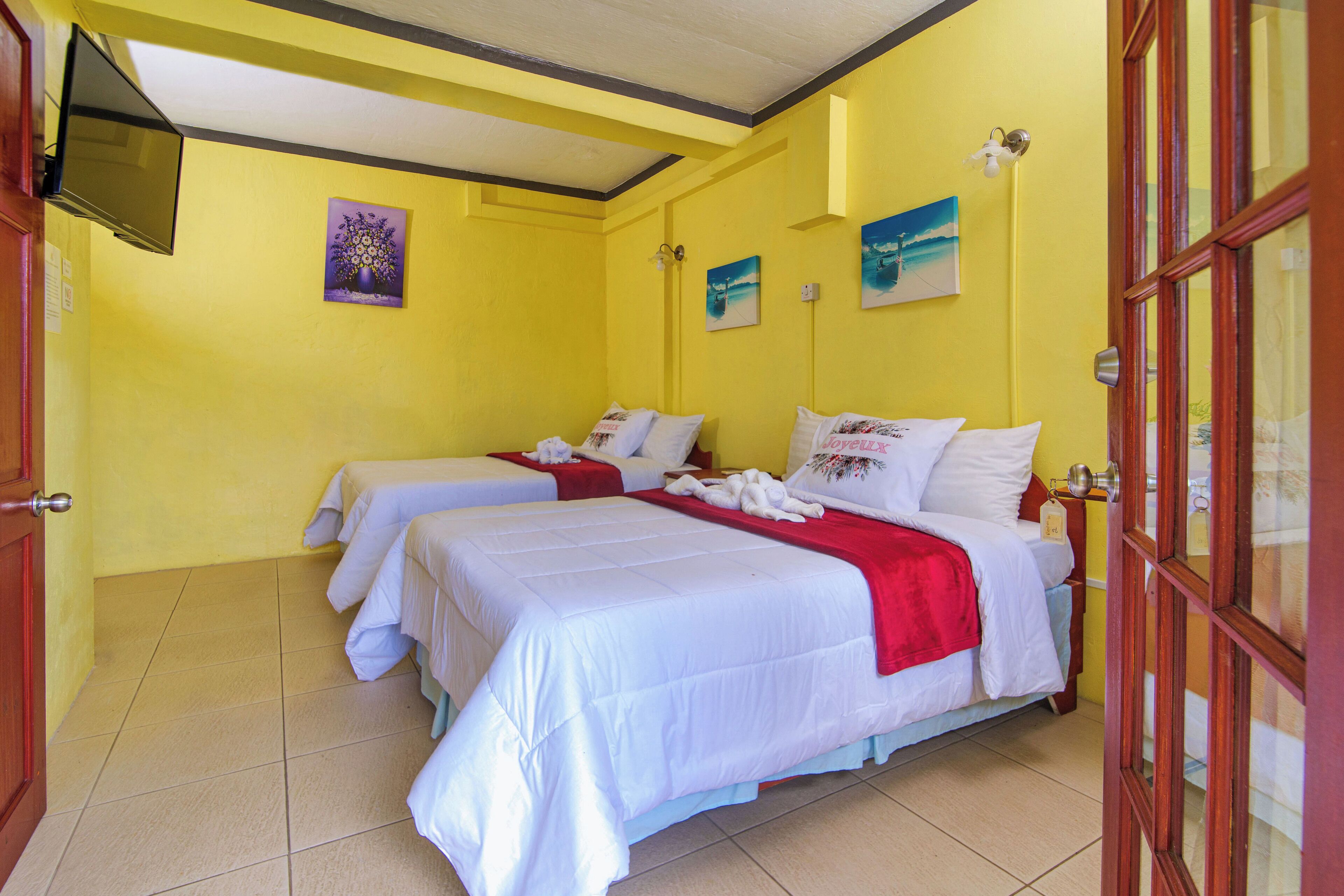 A hotel room with two beds, a TV, and artwork on the walls.