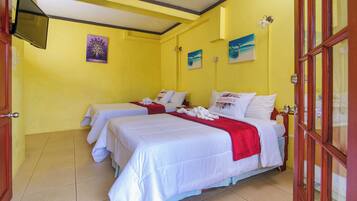 A hotel room with two beds, a TV, and artwork on the walls.