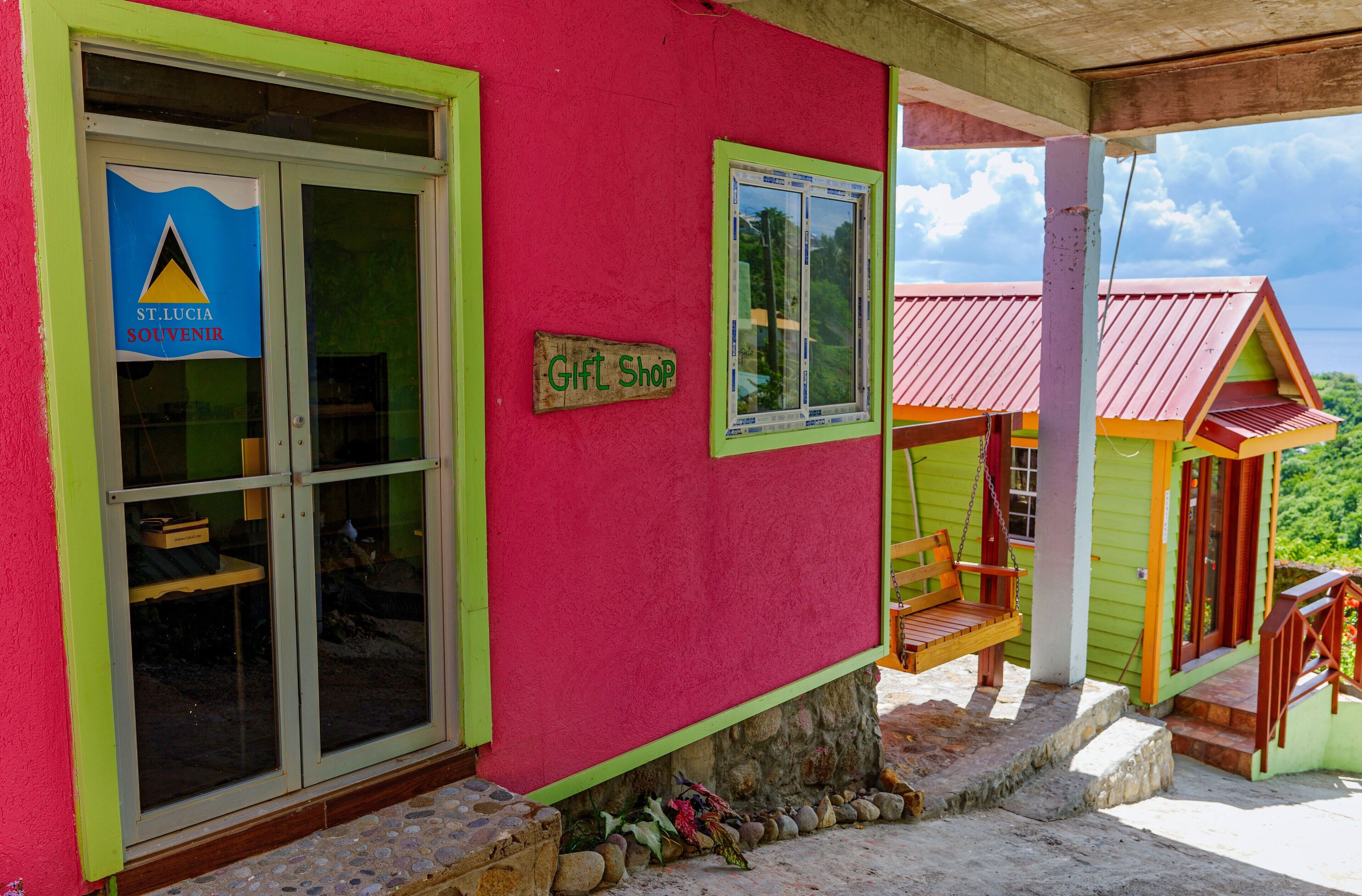 A colorful building with a gift shop sign, a souvenir shop sign, and a wooden swing bench outside.