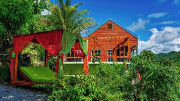 Traditional house amidst lush tropical surroundings, featuring a spacious interior with large windows and a balcony.
