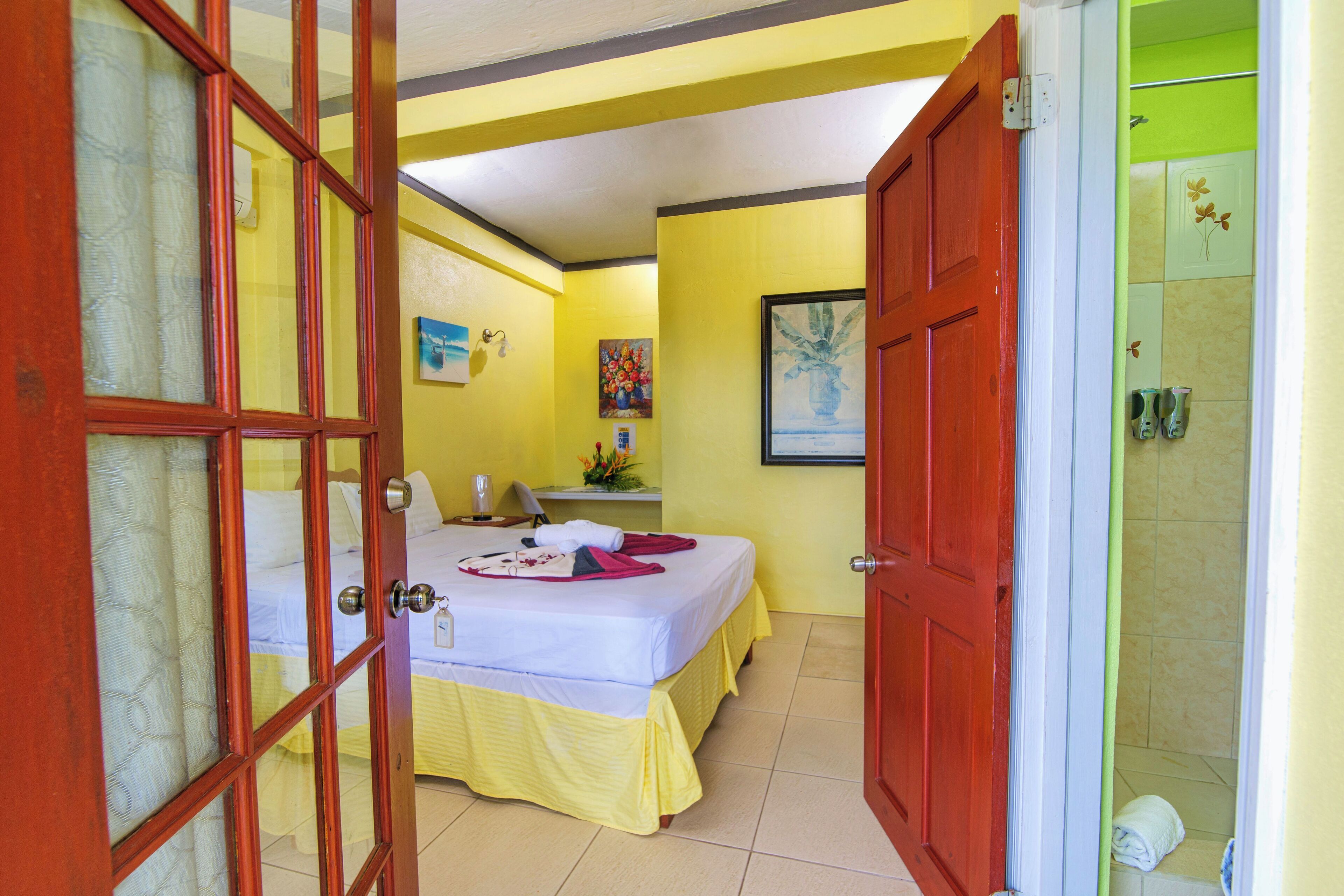 A room with a bed, a desk, and a shower area.