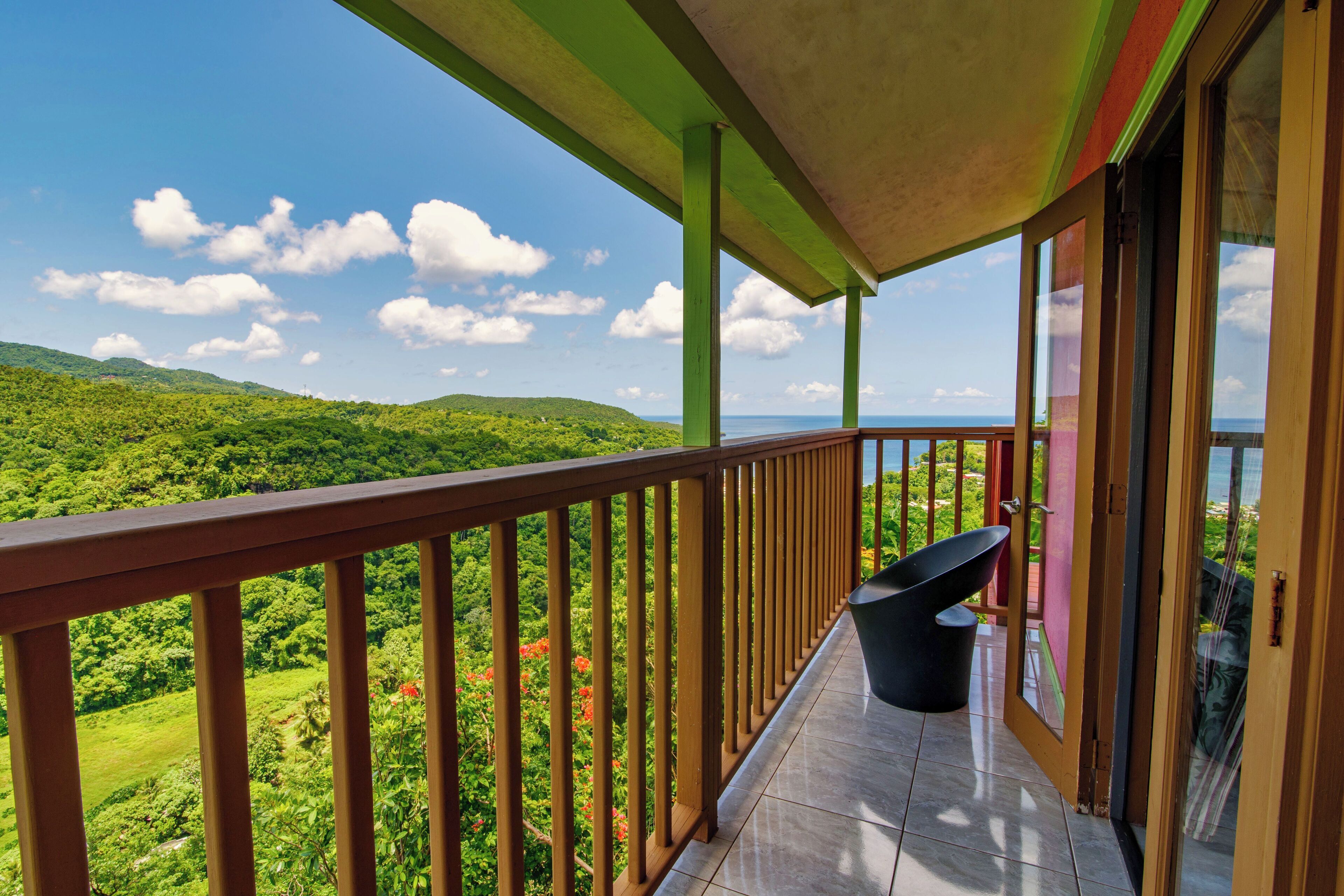 A balcony with a view of lush green hills and a clear sky.