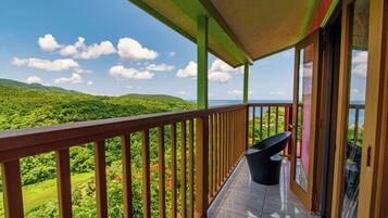 A balcony with a view of lush green hills and a clear sky.