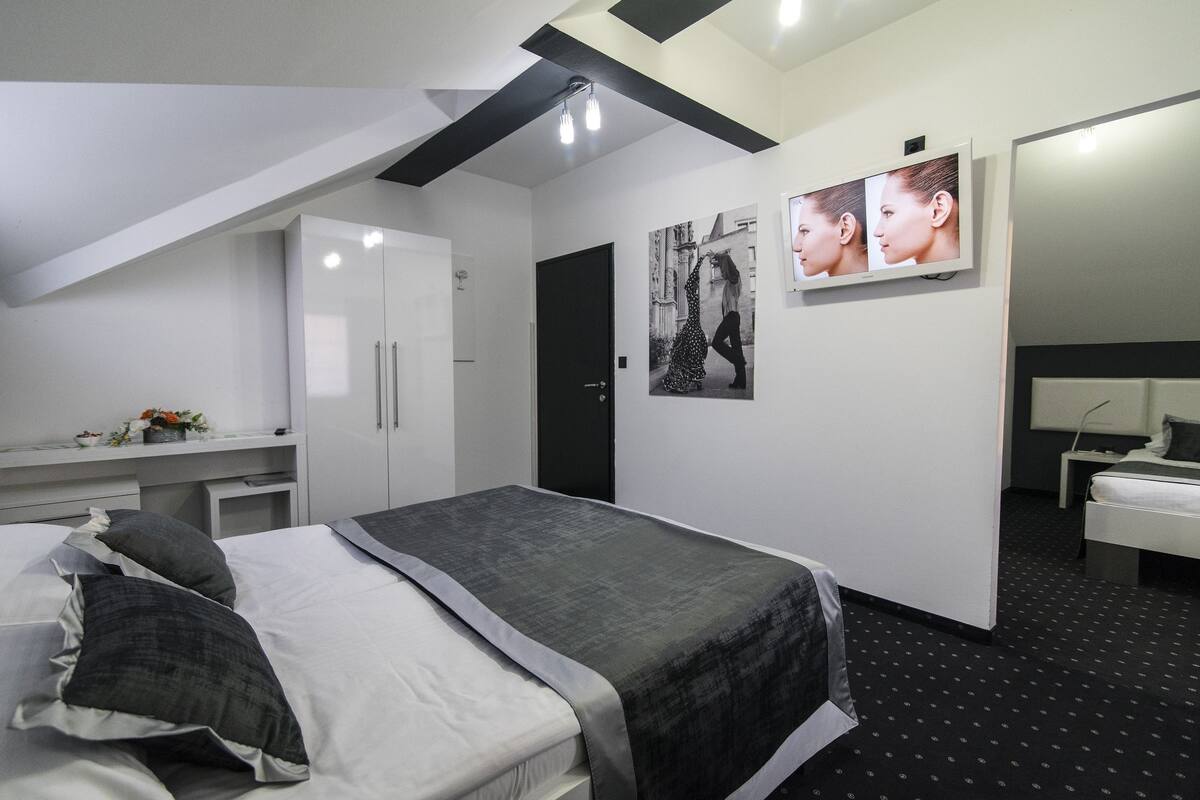 A modern bedroom with a bed, a desk, and a wardrobe.