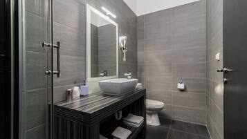 Un baño moderno con un espejo grande, un lavabo, un inodoro y un perchero para toallas.