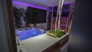 Zona interior de piscina moderna con un panel de control, rodeada de plantas artificiales y una estructura de madera.