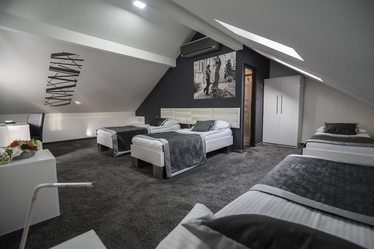 A modern bedroom with two beds, a desk, and a wardrobe.