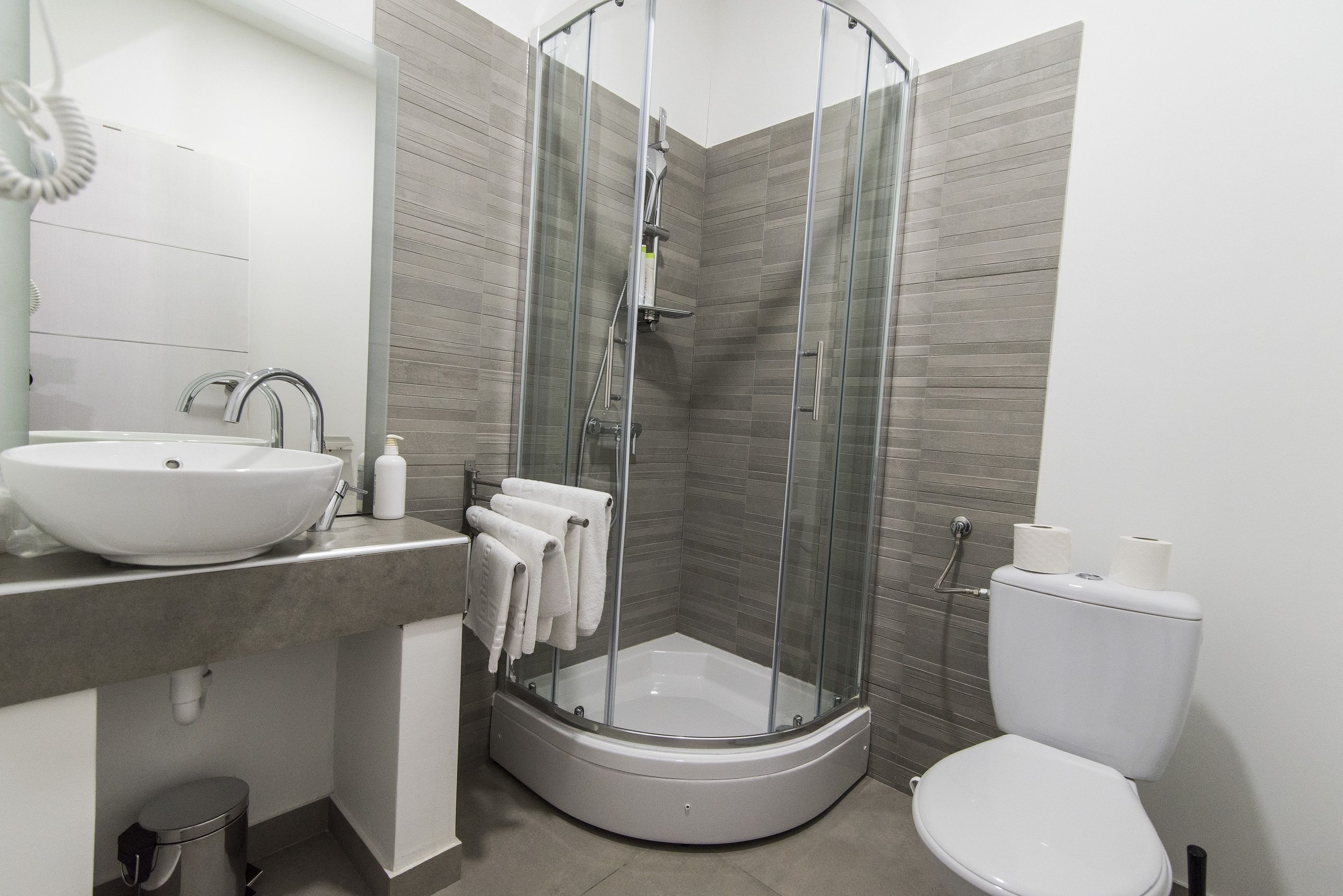 Une salle de bain moderne avec une douche à parois de verre, un lavabo blanc et des toilettes.