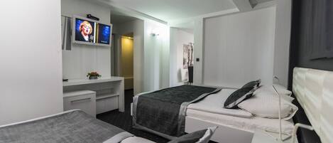 A hotel room with two beds, a desk, a television, and a window.