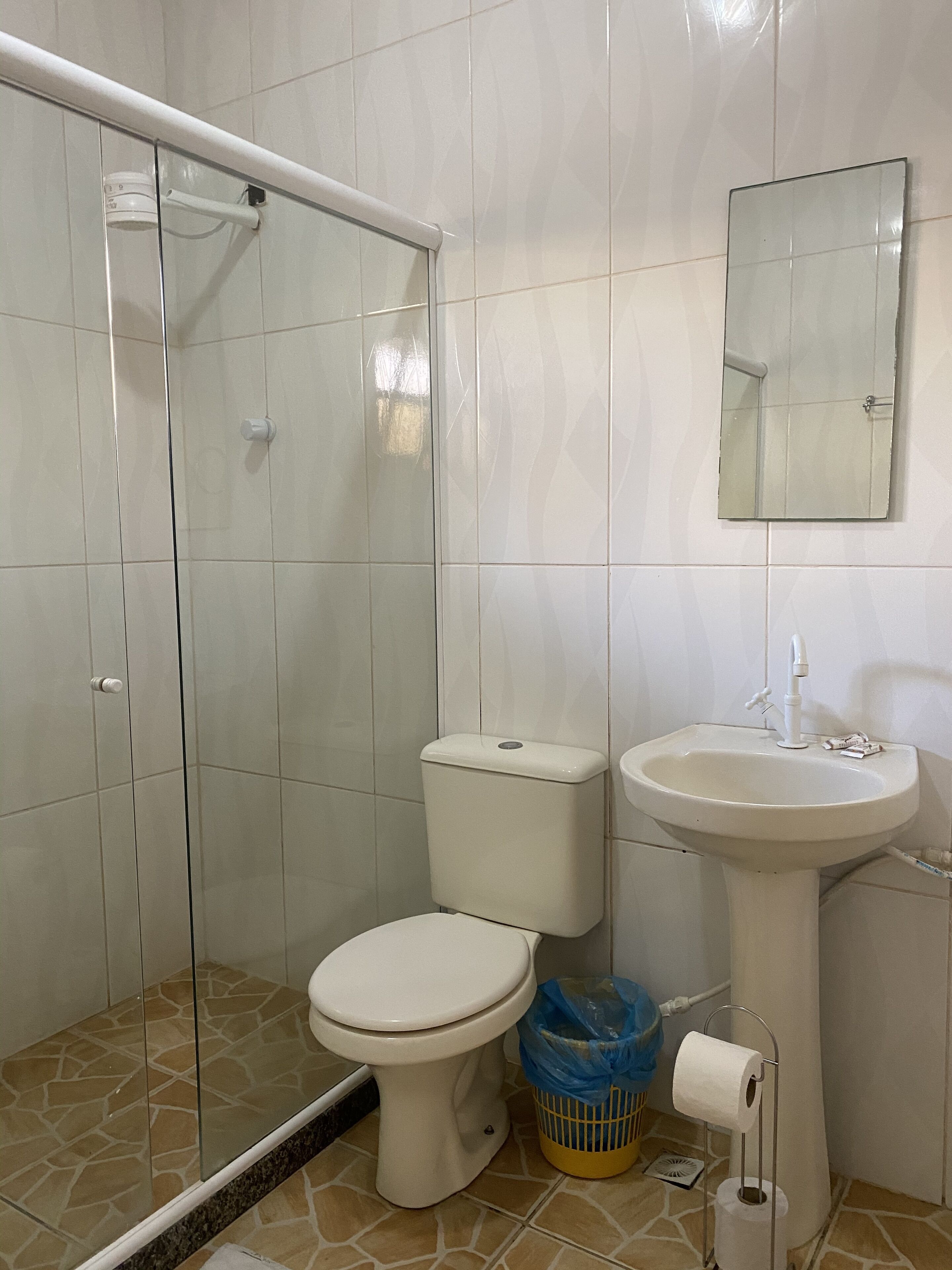 Et badeværelse med toilet, vask og brusebad.