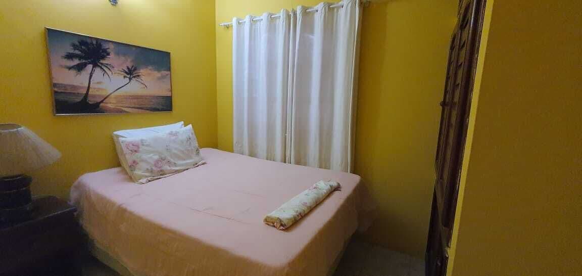 A room with a bed, a painting of a sunset, and a curtain.