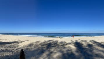 Na praia, areia branca, guarda-sóis, toalhas de praia