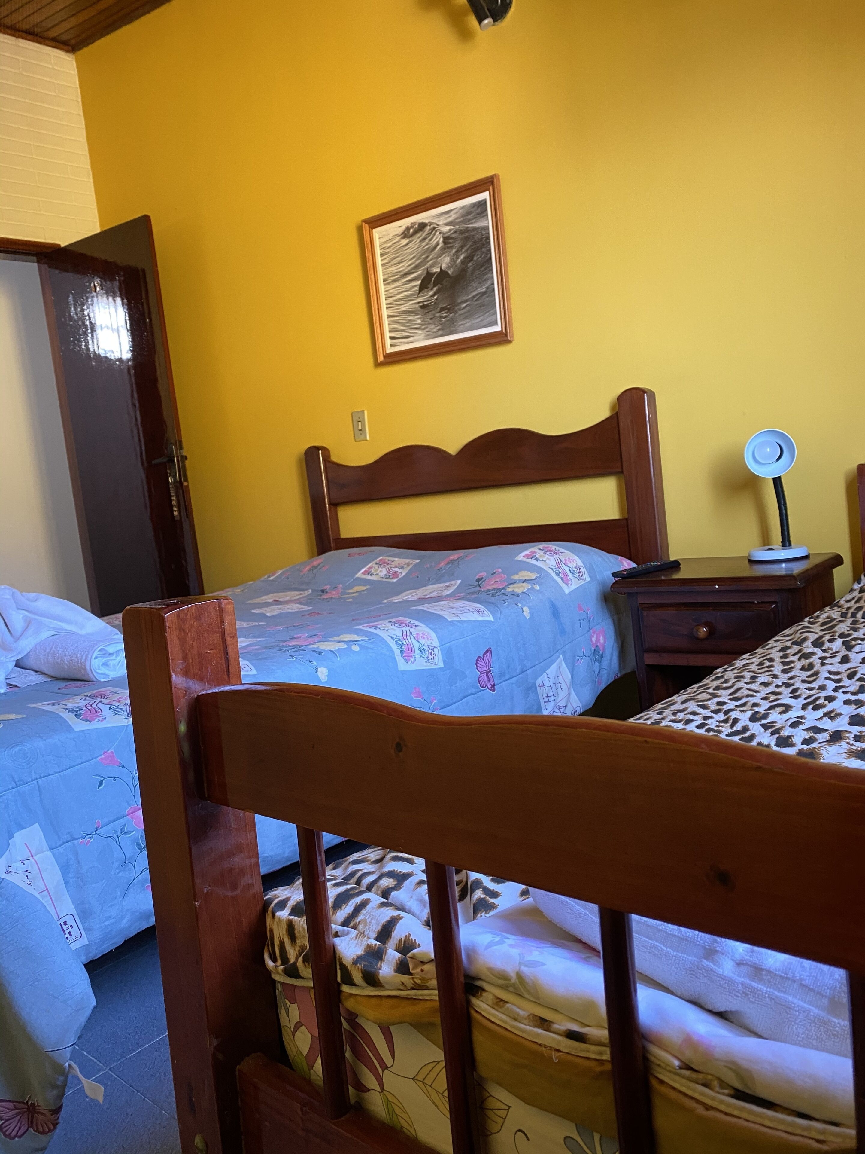 A room with a bed, a nightstand, a lamp, and a framed picture on the wall.
