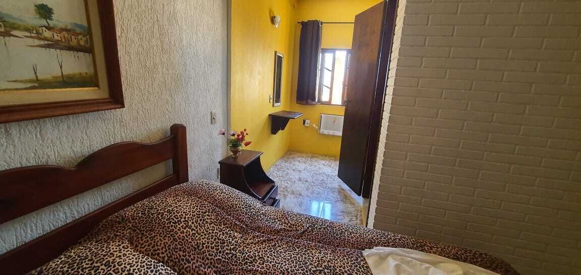 Un dormitorio con cama, mesita de noche, espejo y ventana.