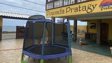 Un trampoline est installé devant un bâtiment sur lequel on peut lire l’inscription « Pousada Pratagy ».