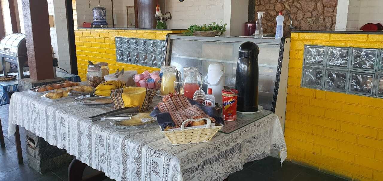Una mesa preparada con diferentes alimentos y condimentos, una parrilla y un muro de ladrillo amarillo.