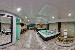 A spa area with a large hot tub, a small pool, and a seating area with chairs and a table.