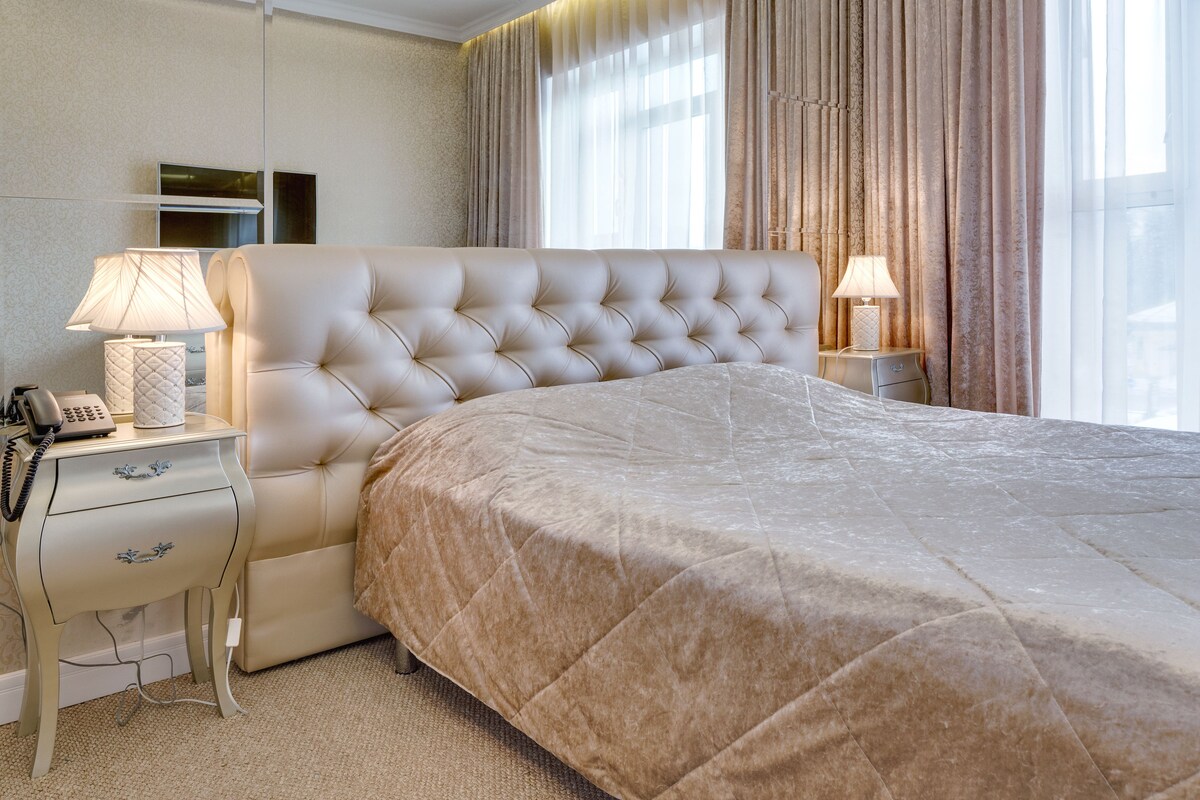 A hotel room with a large bed, a bedside table with a lamp, and a telephone.