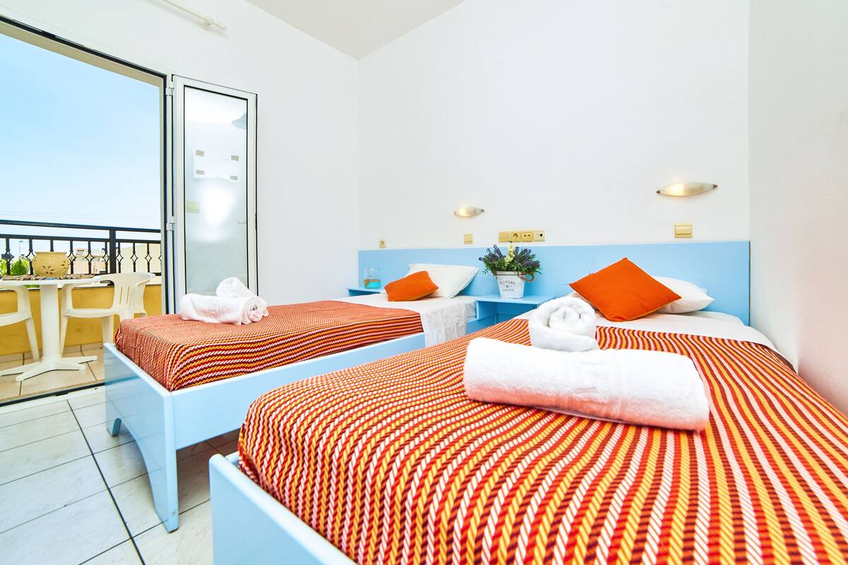 Habitación de hotel con dos camas, un balcón y vistas al mar.