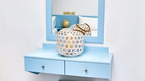 A light blue vanity with a mirror, a small white basket, and a drawer. - Village Oasis (Hersonissos)