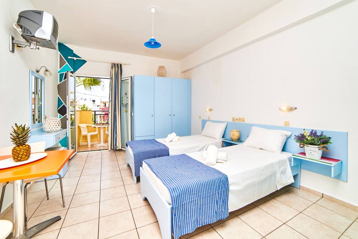 Una habitación de hotel con dos camas, una mesita con una piña, un escritorio y una silla.