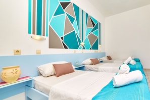 A hotel room with two beds, a decorative wall art, a bedside table with a vase, and a water bottle.