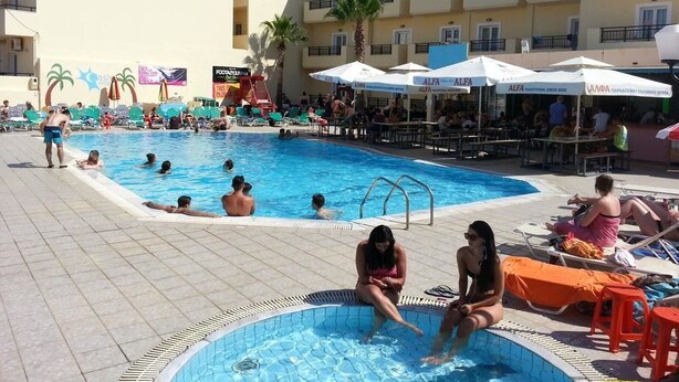 A pool area with multiple swimming pools, sun loungers, and umbrellas. - Village Oasis (Hersonissos)