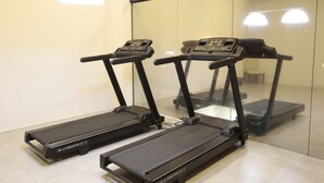 Three treadmills in a room with a glass wall and a ceiling light fixture.