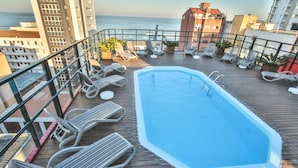 A rooftop pool with lounge chairs and potted plants, overlooking a cityscape and the sea. - Life Hotel Torres (Torres)