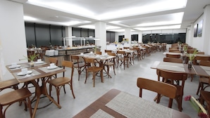 A spacious dining area with multiple tables and chairs, a central serving station, and a large window providing natural light. - Life Hotel Torres (Torres)