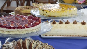 A variety of desserts on display, including cakes and pastries, arranged on a table.